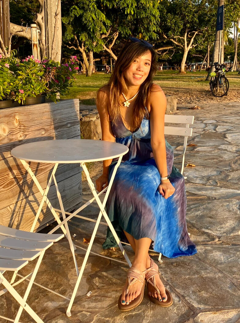 Loree sitting outdoors at a café table, offering accessible cuddling and consent-based touch.