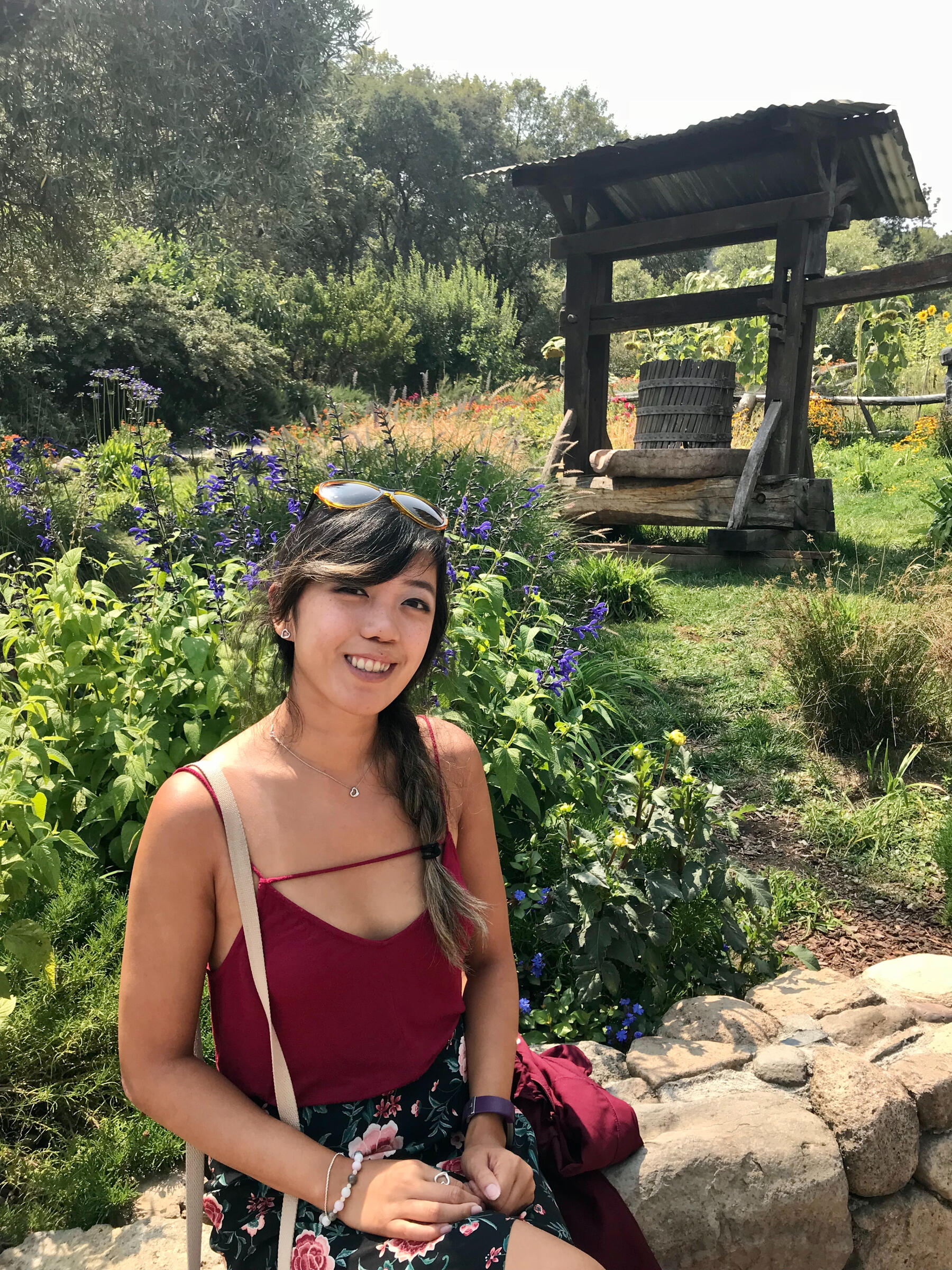 Loree sitting in a garden surrounded by greenery and flowers.